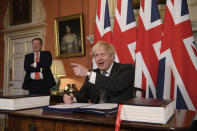 UK chief trade negotiator David Frost looks on as Britain's Prime Minister Boris Johnson signs the EU-UK Trade and Cooperation Agreement at 10 Downing Street, London Wednesday Dec. 30, 2020. The U.K. left the EU almost a year ago, but remained within the bloc’s economic embrace during a transition period that ends at midnight Brussels time —- 11 p.m. in London — on Thursday. European Commission President Ursula von der Leyen and European Council President Charles Michel signed the agreement during a brief ceremony in Brussels on Wednesday morning then the documents were flown by Royal Air Force plane to London for Johnson to add his signature. (Leon Neal/Pool via AP)