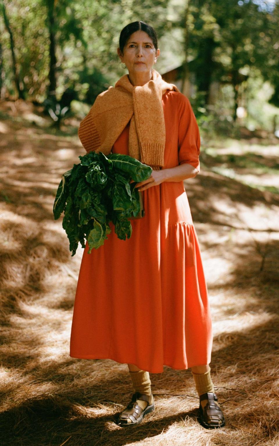 Woman in orange linen dress holding a large cabbage