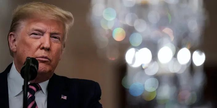 Trump looking confused in front of a chandelier.