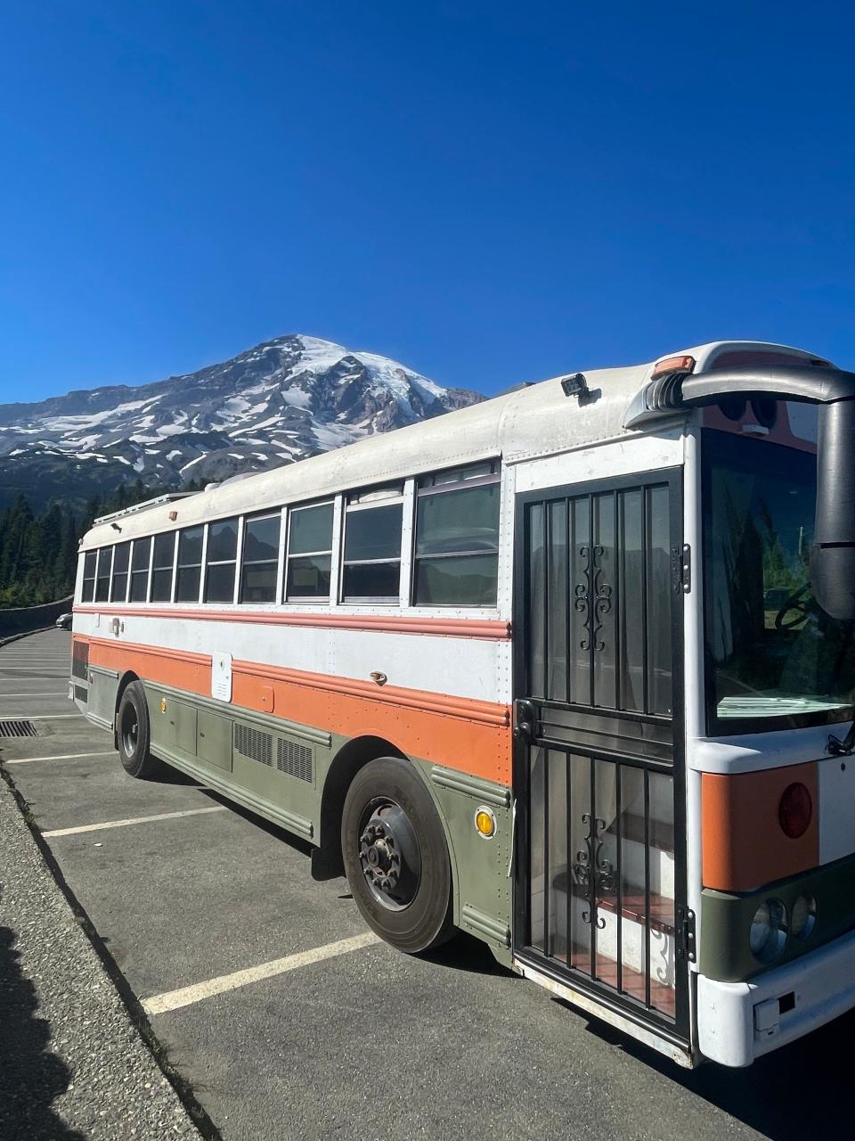 renovated school bus in parking lot with snowy mountain in the background