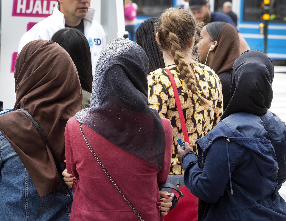 In this Aug. 31, 2018 photo young women listen to a party member of the right wing Sweden Democrats in Stockholm, Sweden. (AP Photo/Michael Probst)