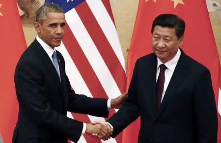 U.S. President Barack Obama (L) shakes hands with China's President Xi Jinping in front of U.S. and Chinese national flags during a joint news conference at the Great Hall of the People in Beijing November 12, 2014. REUTERS/Petar Kujundzic