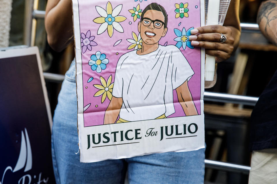 A person hold signs a sign with an illustration of Julio Ramirez (Julius Constantine Motal / NBC News)