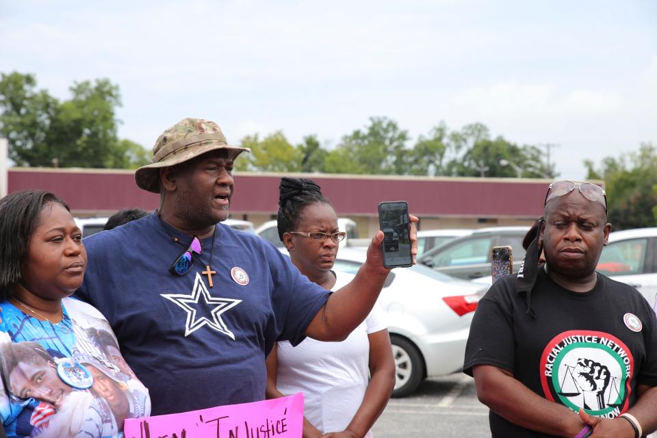 Timothy Lee, uncle of Saudi Arai Lee, shows an image of his nephew walking on the sidewalk, moments before his death, during a speech before marching to city hall on Saturday, July 16, 2022