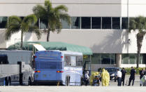 Paramedics wearing yellow protective suits to protect the spread of coronavirus, stand at the ready as passengers that came off the cruise ship Rotterdam Thursday, get off a bus to board a charter plane at Fort Lauderdale–Hollywood International Airport, Friday, April 3, 2020, in Fort Lauderdale, Fla. The Zaandam and a sister ship sent to help it, the Rotterdam, were given permission to unload passengers at Port Everglades on Thursday, after days of negotiations with officials who feared it would divert resources from a region with a spike in virus cases. (AP Photo/Wilfredo Lee)