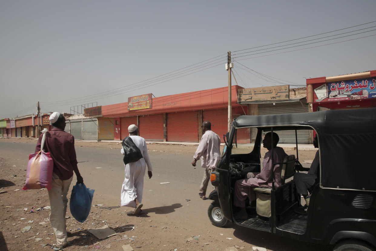 CORRECTS THE DATE People walk past shuttered shops in Khartoum, Sudan, Monday, April 17, 2023. Sudan's embattled capital has awoken to a third day of heavy fighting between the army and a powerful rival force for control of the country. Airstrikes and shelling intensified on Monday in parts of Khartoum and the adjoining city of Omdurman. (AP Photo/Marwan Ali)