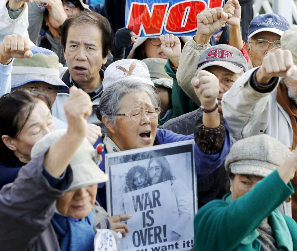 People stage a protest as construction workers start dumping a truckload of sediment into the sea at Henoko on Okinawa's east coast Friday, Dec. 14, 2018. Japan's central government has started main reclamation work at a disputed U.S. military base relocation site on the southern island of Okinawa despite fierce local opposition. (Takuto Kaneko/Kyodo News via AP)