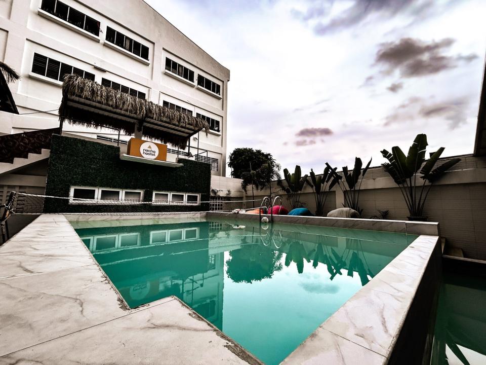 A large swimming pool next to a bar area on a patio outside a hotel.