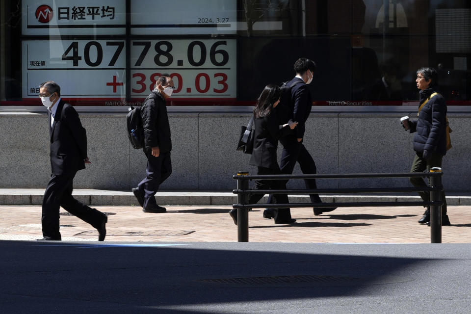 People walk in front of an electronic stock board showing Japan's Nikkei 225 index at a securities firm Wednesday, March 27, 2024, in Tokyo. Asian shares were mixed on Wednesday after Wall Street slipped a bit further from its record highs. (AP Photo/Eugene Hoshiko)