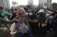 People march protesting against the new jobs law in Jakarta, Indonesia, Tuesday, Oct. 20, 2020. Protests against Indonesia's new jobs law were held in cities across the country on Tuesday, with demonstrators calling on the president to revoke the legislation they say will erode labor rights and weaken environmental protections. (AP Photo/Achmad Ibrahim)