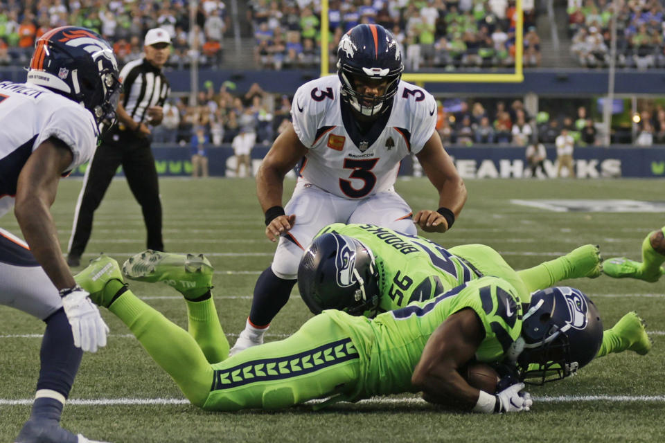 Denver Broncos quarterback Russell Wilson (3) watches as Seattle Seahawks cornerback Mike Jackson, front, recovered the football after it was fumbled by Broncos running back Javonte Williams during the second half of an NFL football game, Monday, Sept. 12, 2022, in Seattle. (AP Photo/John Froschauer)