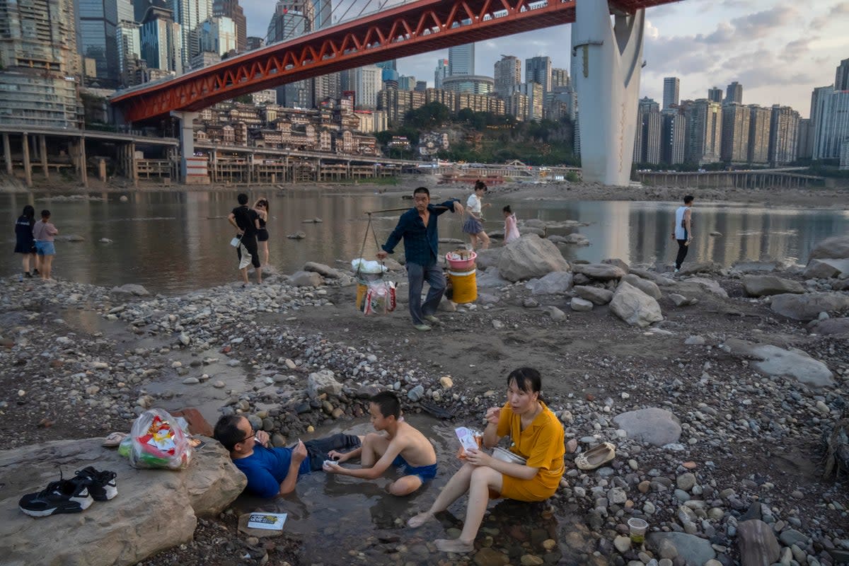 People sit in a shallow pool of water in the riverbed of the Jialing River, a tributary of the Yangtze, in southwestern China's Chongqing  (AP)
