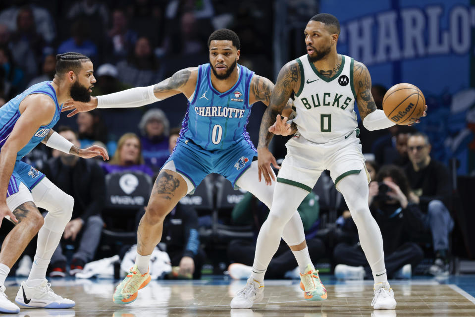 Milwaukee Bucks guard Damian Lillard, right, looks to pass the ball against Charlotte Hornets forwards Miles Bridges, center, and Cody Martin, left, during the first half of an NBA basketball game in Charlotte, N.C., Thursday, Feb. 29, 2024. (AP Photo/Nell Redmond)