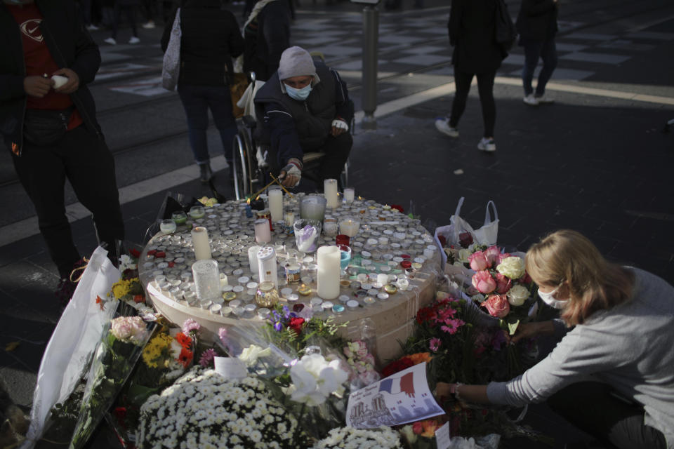 people set flowers, messages and candles in front of the Notre Dame church, in Nice, France, Friday, Oct. 30, 2020. A new suspect is in custody in the investigation into a gruesome attack by a Tunisian man who killed three people in a French church. France heightened its security alert amid religious and geopolitical tensions around cartoons mocking the Muslim prophet. (AP Photo/Daniel Cole)
