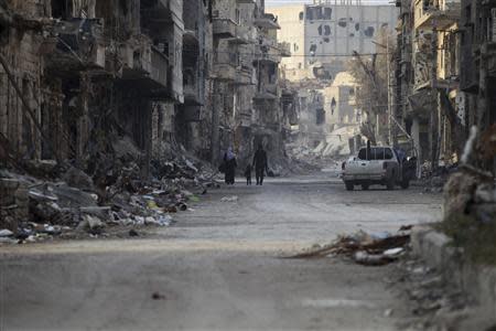 A Free Syrian Army fighter walks with his family through damage and debris along a street Deir al-Zor, eastern Syria November 29, 2013.Picture taken November 29, 2013. REUTERS/Khalil Ashawi