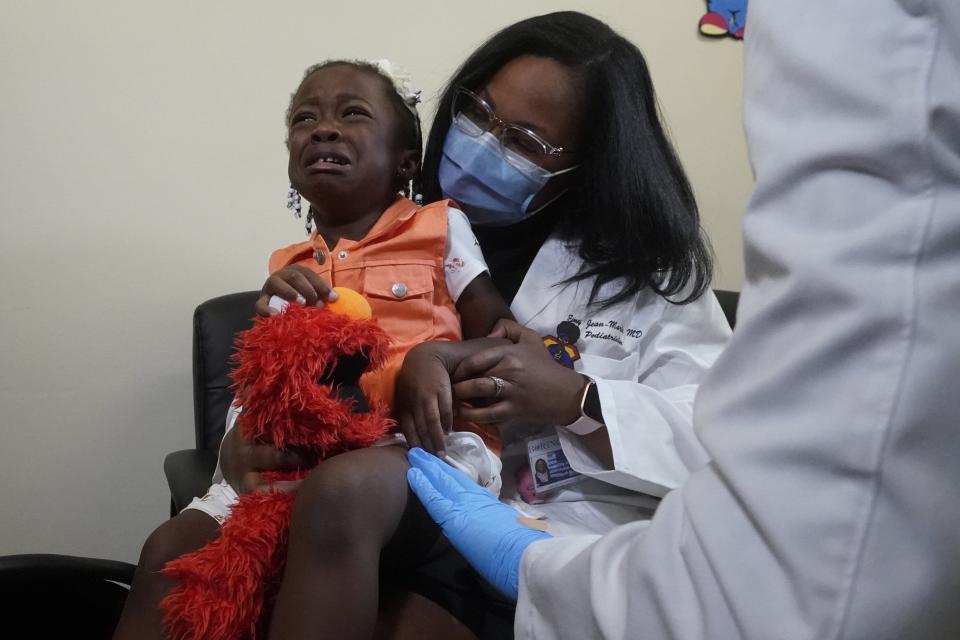 Pediatrician Emy Jean-Marie, right, holds her daughter Emiola Adebayo, 3, on her lap as the girl reacts after receiving a vaccine, Tuesday, June 28, 2022, at the Borinquen Health Care Center in Miami. Florida is the only state that didn't pre-order the under-5 vaccine, and state Surgeon General Joseph Ladapo has recommended against vaccinating healthy children. (AP Photo/Wilfredo Lee)