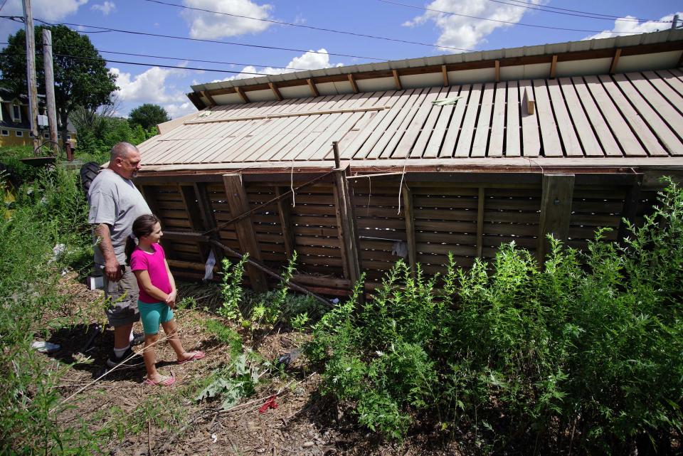 Todd Wilbur, owner and operator of a farm on Poquanticut Avenue in Easton, and his daughter Gracie, 8, on Monday, July 31, 2023, take a look at their corn crib, which was overturned when a tornado touched down Saturday, July 29, 2023.