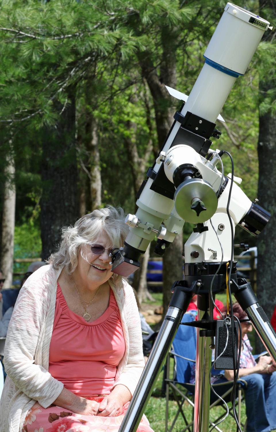 Karen Sotelo looks through a telescope set up by members of the Cleveland County Astronomical Society as people gathered to watch the eclipse Monday afternoon, April 8, 2024, at the Gateway Trail in Kings Mountain.