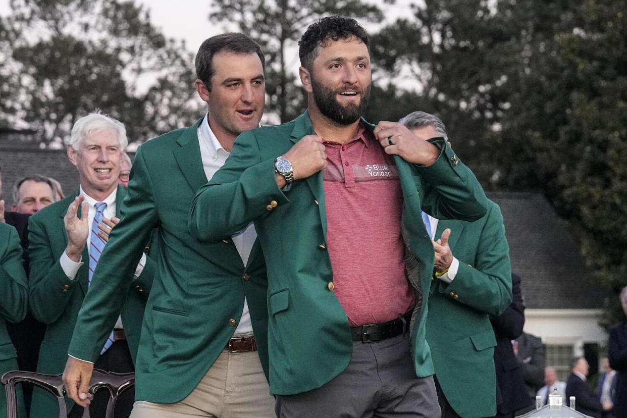 Scottie Scheffler puts the green jacket on Jon Rahm, of Spain, after Rahm won the 2023 Masters.