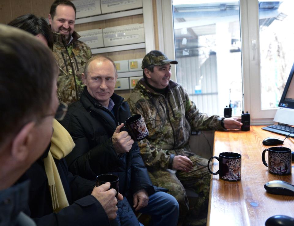 Russian President Vladimir Putin, center, visits the snow leopard sanctuary in the Russian Black Sea resort of Sochi, Tuesday, Feb. 4, 2014. Putin checked in Tuesday at a preserve for endangered snow leopards and visited a group of cubs born last summer in the mountains above the growing torrent of activity in Sochi for the Winter Games. At right is director of the preserve Umar Semyonov. (AP Photo/RIA-Novosti, Alexei Nikolsky, Presidential Press Service)