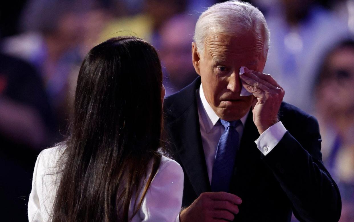 Joe Biden wipes his eyes upon arriving on stage to speak on the first day of the Democratic National Convention