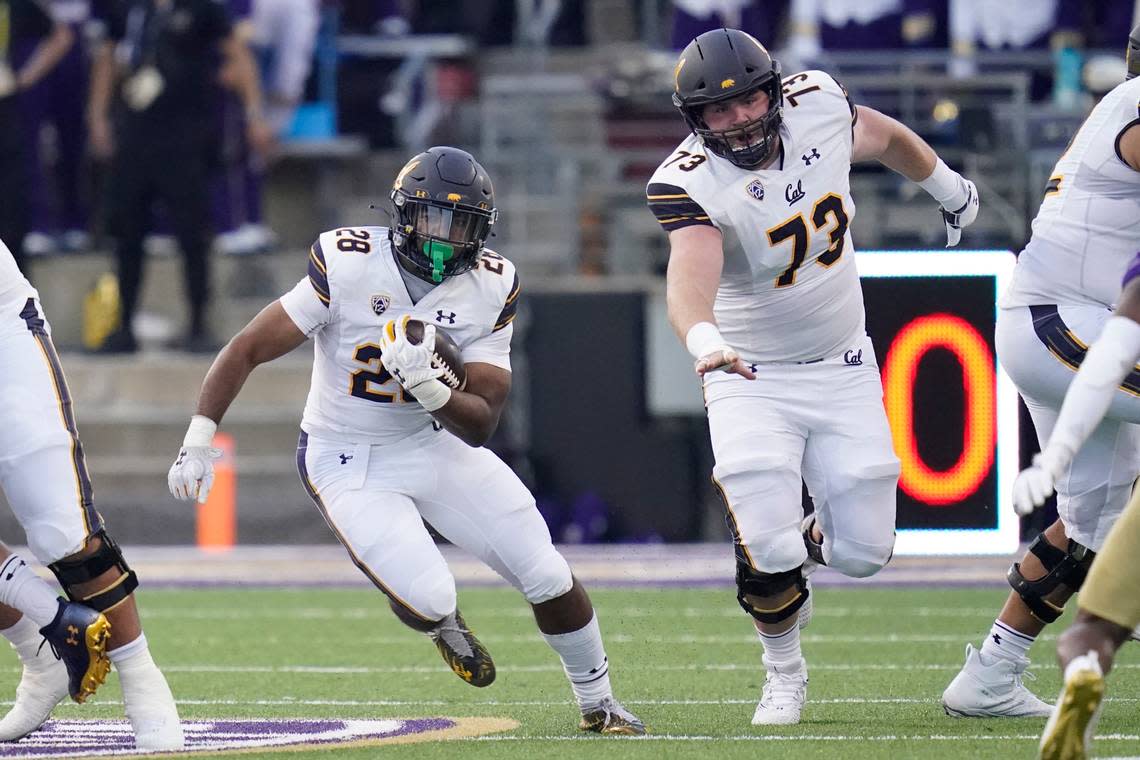 California running back Damien Moore (28) rushes as offensive lineman Matthew Cindric (73) blocks during the first half of an NCAA college football game against Washington, Saturday, Sept. 25, 2021, in Seattle. (AP Photo/Elaine Thompson)