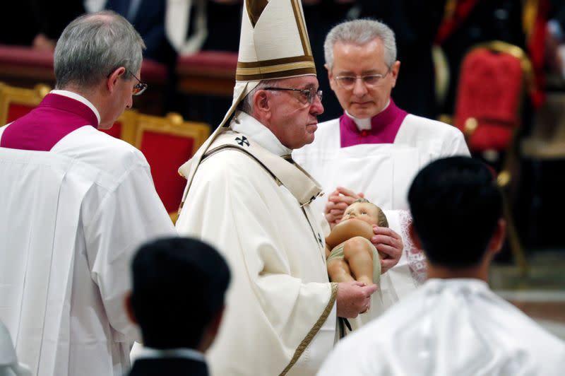 Pope Francis carries a statue of Baby Jesus during the Christmas Eve mass in Saint Peter's Basilica at the Vatican