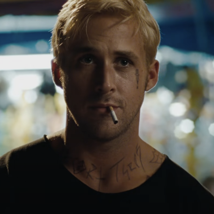 Ryan with a brooding expression and a cigarette in his mouth, visible tattoos, standing in a dimly lit area with lights in the background