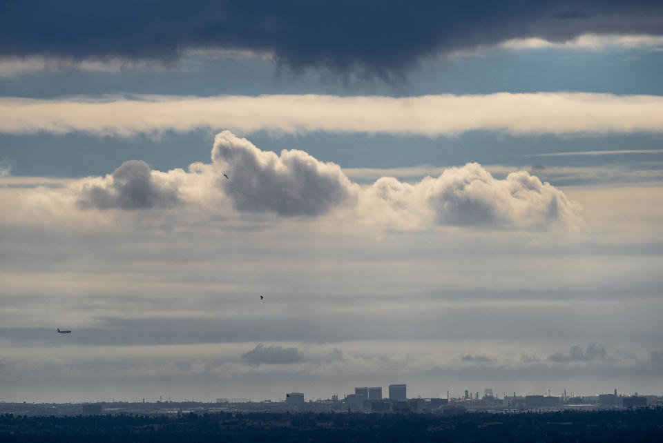 A plane descends into Los Angeles International Airport as low clouds gather over the Pacific ahead of forecasted rain in Los Angeles, Sunday, Feb. 18, 2024. (AP Photo/Damian Dovarganes)