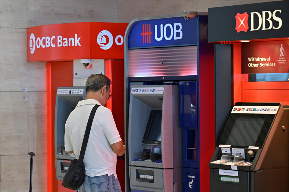 A man uses an automated teller machine (ATM) in Singapore, illustrating a story on most-searched stocks on Yahoo in Singapore in 2023, including OCBC, UOB and DBS.