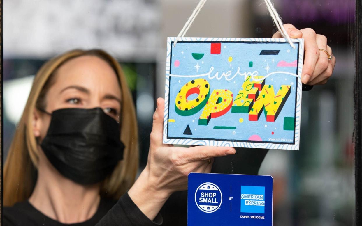  EDITORIAL USE ONLY Manager Louise Hughes from Muse of London displays a "we're open" sign designed by artist Yukai Du, which has been created as part of the American Express Shop Small campaign and to help welcome people back to our high streets. London. PA Photo. Issue date: Monday April 12, 2021.  - David Parry/PA Wire