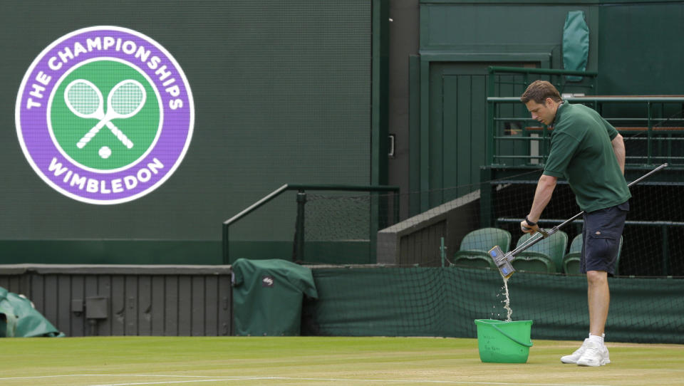 FILE - In this July 13, 2017, file photo, Ben Sidgwick wrings out his mop on Center Court at the All England Club at the Wimbledon Tennis Championships in London. Wimbledon was first played in 1877 and is the oldest Grand Slam tennis tournament. (AP Photo/Alastair Grant, File)