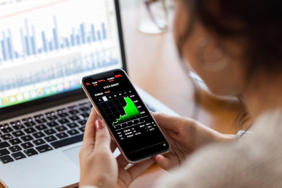 Person holding a phone displaying a stock chart.