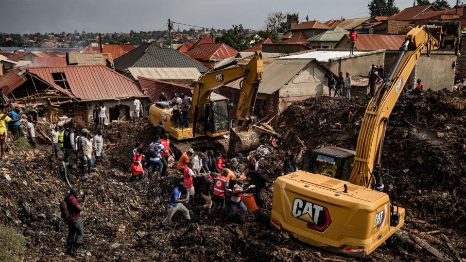 Two excavators and rescuers dig through huge piles of rubbish