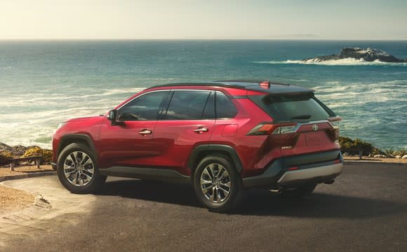 A red 2019 Toyota RAV4, a compact crossover SUV, parked in an oceanfront parking lot.