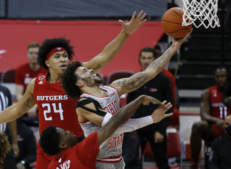 Ohio State guard Duane Washington, right, goes up for a shot against Rutgers guard Ron Harper, top, and guard Montez Mathis during the first half of an NCAA college basketball game in Columbus, Ohio, Wednesday, Dec. 23, 2020. (AP Photo/Paul Vernon)