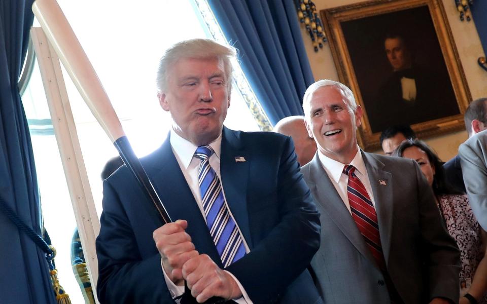 Vice President Mike Pence laughs as U.S. President Donald Trump holds a baseball bat as they attend a Made in America product showcase event  - Credit: Reuters
