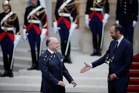 Newly-appointed French Prime Minister Edouard Philippe (R) reacts with his predecessor Bernard Cazeneuve (L) during a handover ceremony at the Hotel Matignon, in Paris, France, May 15, 2017. REUTERS/Benoit Tessier