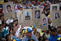 Manifestantes sostienen pancartas con las fotografías de venezolanos que murieron en las protestas de la últimas semanas durate una manifestación opositora en Caracas, Venezuela, el viernes 28 de febrero de 2014. (AP foto/Rodrigo Abd)