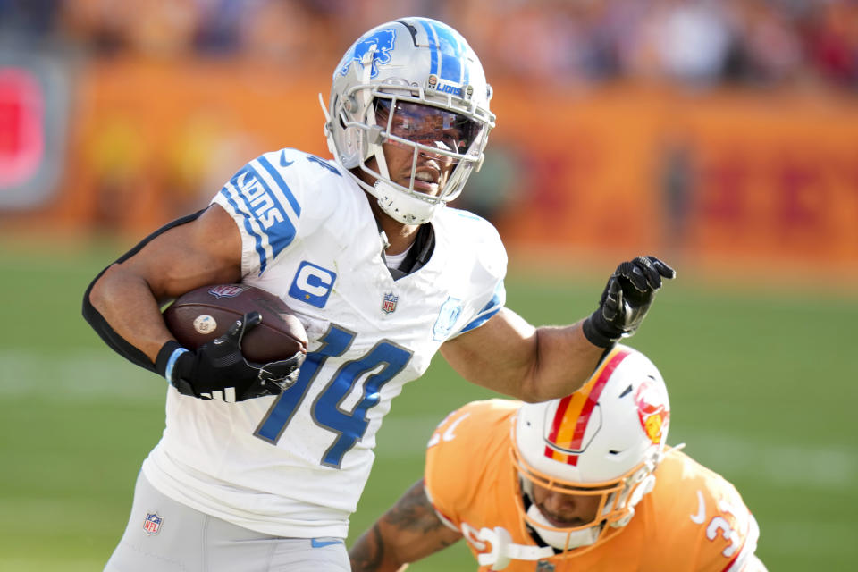 Detroit Lions wide receiver Amon-Ra St. Brown (14) avoids the tackle of Tampa Bay Buccaneers safety Antoine Winfield Jr. (31) on a 27-yard touchdown reception during the first half of an NFL football game Sunday, Oct. 15, 2023, in Tampa, Fla. (AP Photo/Chris O'Meara)