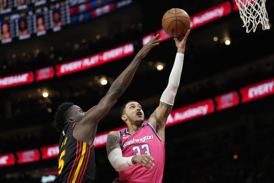 Washington Wizards forward Kyle Kuzma (33) scores as Atlanta Hawks center Clint Capela (15) defends during the first half of an NBA basketball game Tuesday, Feb. 28, 2023, in Atlanta. (AP Photo/John Bazemore)