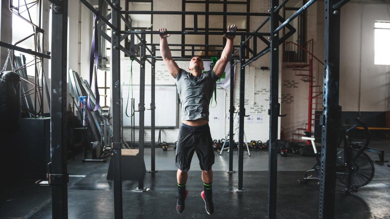  Man performing a pull up in the gym . 