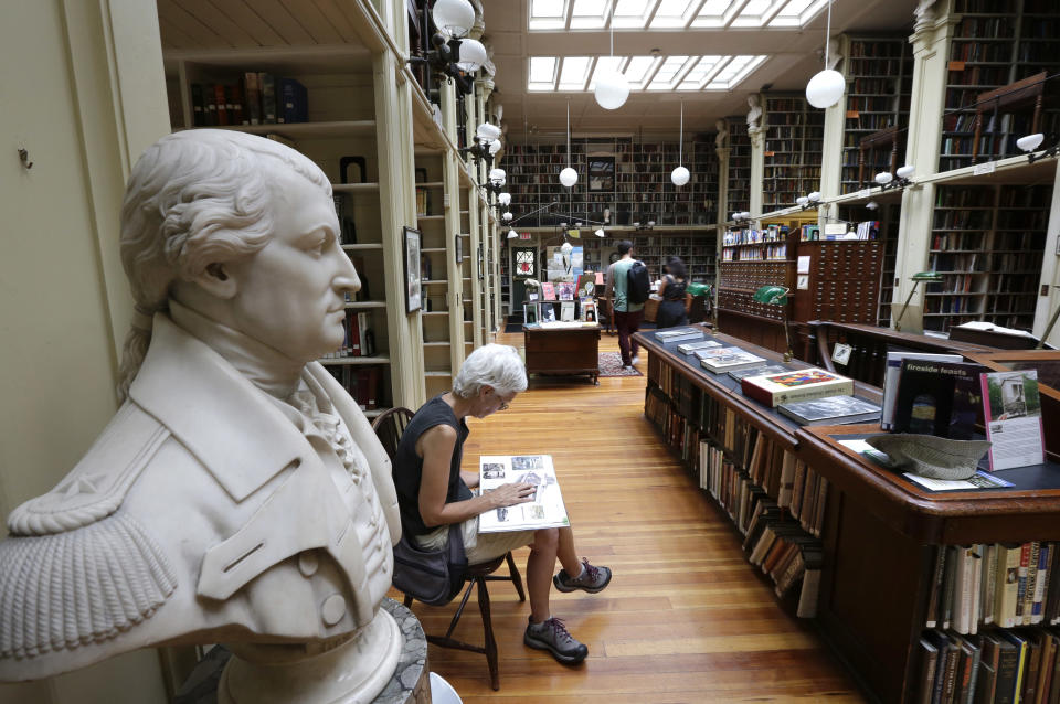 A woman reads while seated next a statue of American Revolutionary War Gen. Nathanael Greene, left, at the Providence Athenaeum, in Providence, R.I. on Monday, July 15, 2013. With roots dating back to 1753, the private library is one of the oldest in the country. It is housed in a Greek Revival-style granite building that neighbors Brown University and the Rhode Island School of Design. (AP Photo/Steven Senne)