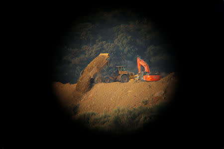 A truck pours sand next to a digger next to the area where Julen, a Spanish two-year-old boy who fell into a 25-centimetre (9.8 inch) wide and around 100-metre (328 feet) deep well four days ago when the family was taking a stroll through a private estate, in Totalan, southern Spain, January 17, 2019. REUTERS/Jon Nazca