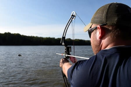 Dan Steenwyk, 29, an HVAC technician from Hudson, Michigan, lines up a shot while hunting Asian carp with bow and arrow on the Illinois River near Lacon