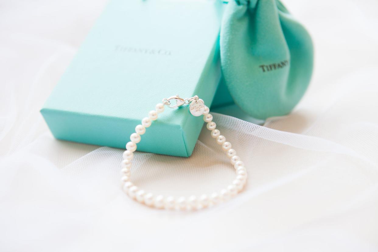 Tiffany+ Co. pearl bracelet, gift bag and gift box shot on a veil background.