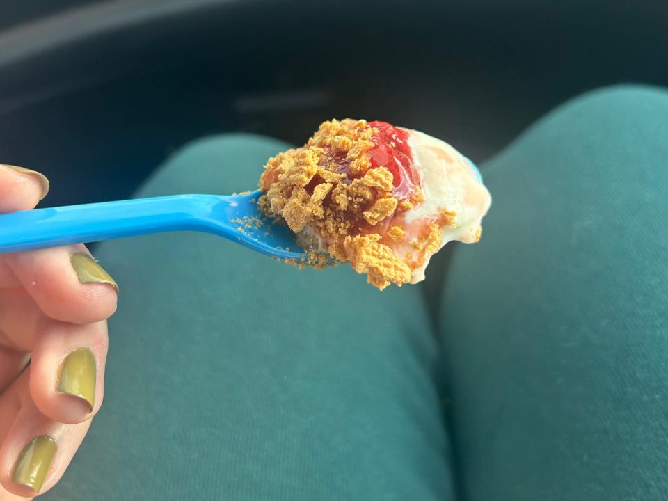 bite of strawberry cheesecake sundae on a blue plastic spoon