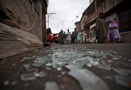 Kashmiris walk past broken window glass after clashes between protesters and the security forces on Friday evening, in Srinagar