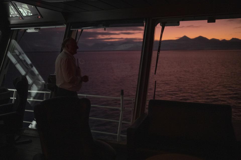 The first officer on a ship Svalbard’s governor lent looks out at Rayleigh-scatterings on the horizon during a journey from Longyearbyen to Barentsburg, Norway, Saturday, Jan. 7, 2023. The children’s choir from the Lutheran church in the Arctic archipelago of Svalbard traveled three hours each way by boat to mark Orthodox Christmas with the 40 children in Barentsburg, a village owned by Russia’s Arctic mining company in the remote Norwegian territory. (AP Photo/Daniel Cole)