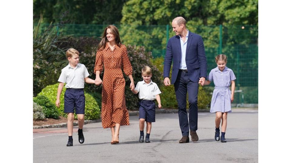 Prince George, Kate Middleton, Prince Louis, Prince William and Princess Charlotte walking towards a school